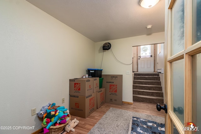 interior space featuring stairway, light wood-type flooring, and a textured ceiling