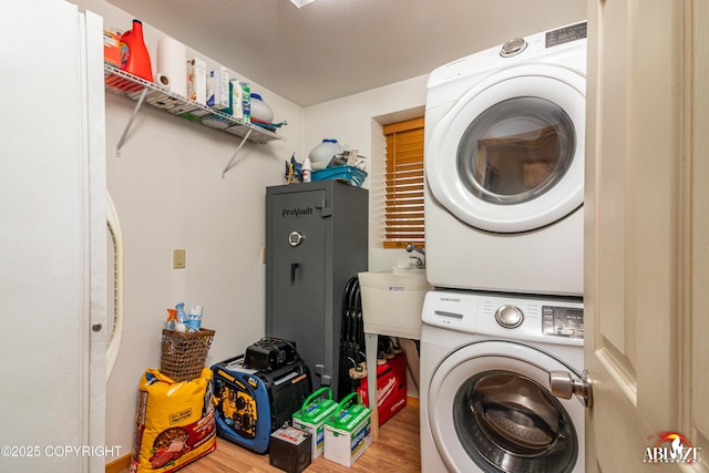 laundry room featuring a sink, wood finished floors, laundry area, and stacked washer / dryer