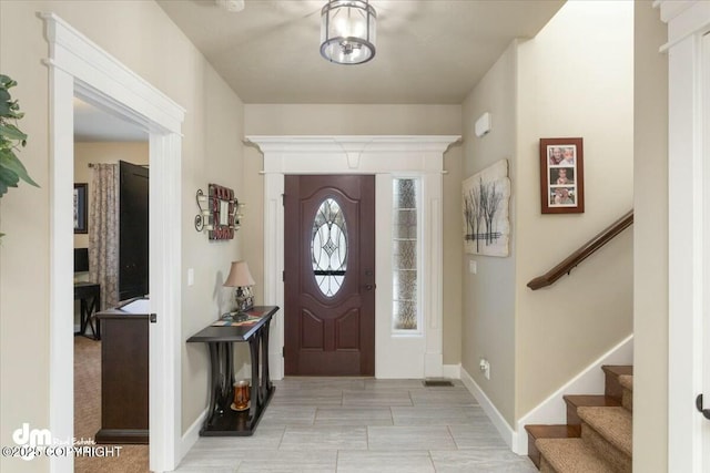 foyer entrance with stairway and baseboards