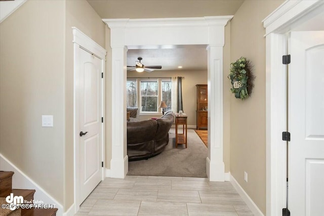 hallway with stairs, baseboards, and ornate columns