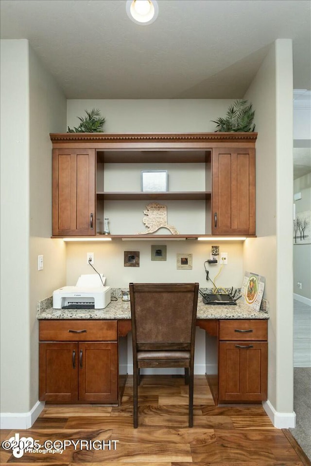 kitchen featuring open shelves, wood finished floors, brown cabinets, and built in study area