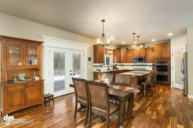 dining area featuring dark wood finished floors, an inviting chandelier, recessed lighting, and french doors