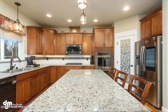 kitchen featuring backsplash, pendant lighting, appliances with stainless steel finishes, brown cabinetry, and a sink