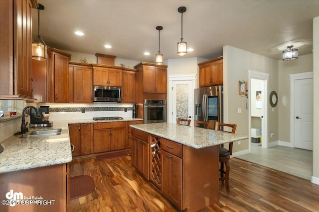 kitchen featuring decorative backsplash, brown cabinets, appliances with stainless steel finishes, a kitchen breakfast bar, and a sink