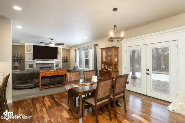 dining space featuring dark wood finished floors, a ceiling fan, french doors, and a fireplace