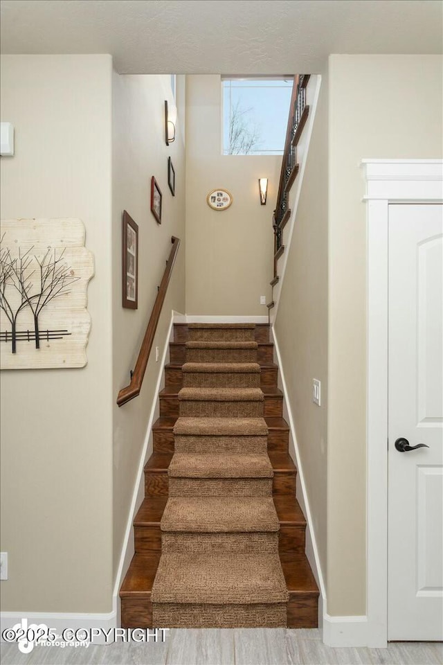 stairs with wood finished floors and baseboards