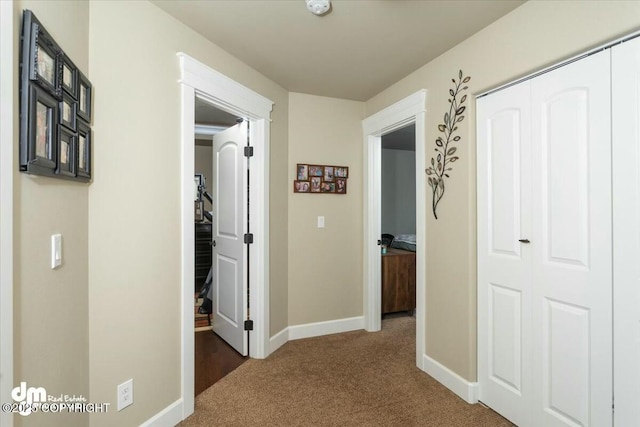 hallway with carpet flooring and baseboards