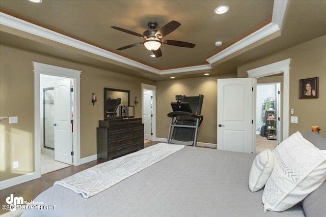 bedroom with a tray ceiling, wood finished floors, recessed lighting, crown molding, and baseboards