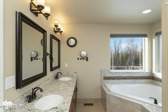 full bath featuring double vanity, tiled tub, and a sink