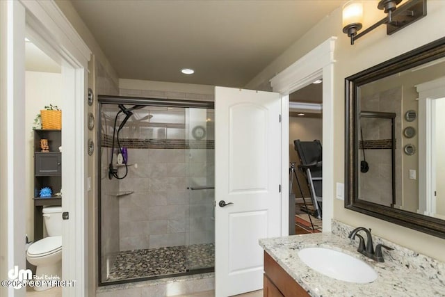 bathroom with toilet, a stall shower, and vanity