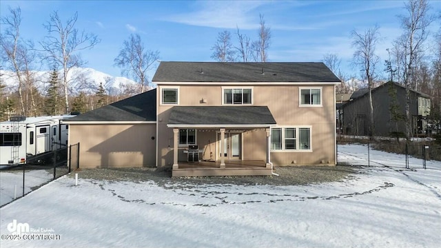 snow covered back of property featuring fence and a wooden deck