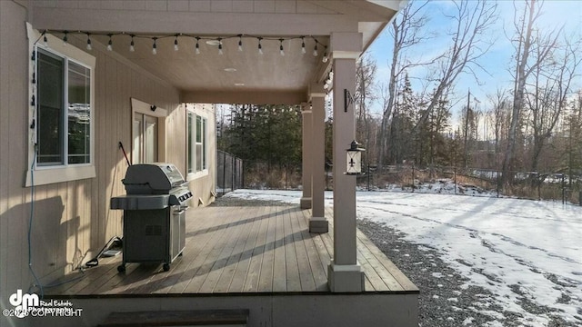 snow covered deck featuring grilling area and fence