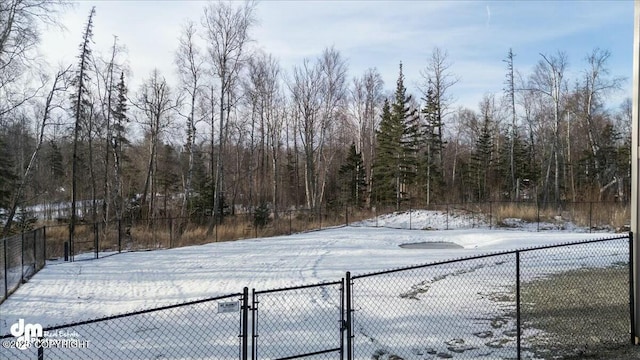 yard layered in snow with fence and a view of trees