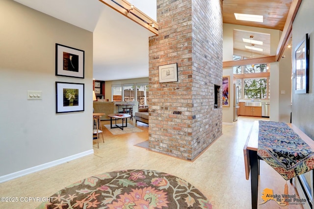 hallway with a sink, baseboards, a wealth of natural light, and a towering ceiling