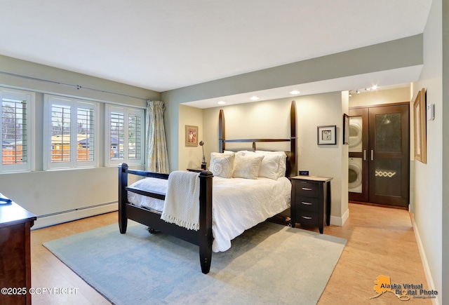 bedroom with light wood-style floors, a baseboard heating unit, baseboards, and stacked washer and dryer