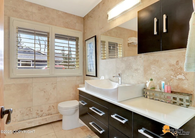 bathroom with toilet, tile walls, vanity, and tile patterned flooring