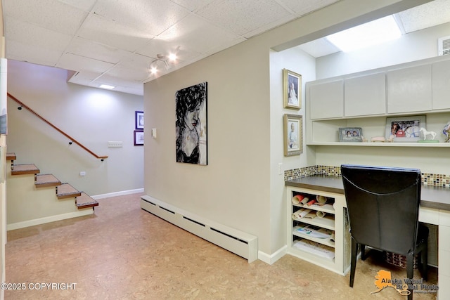 interior space with light floors, visible vents, baseboards, a paneled ceiling, and a baseboard heating unit