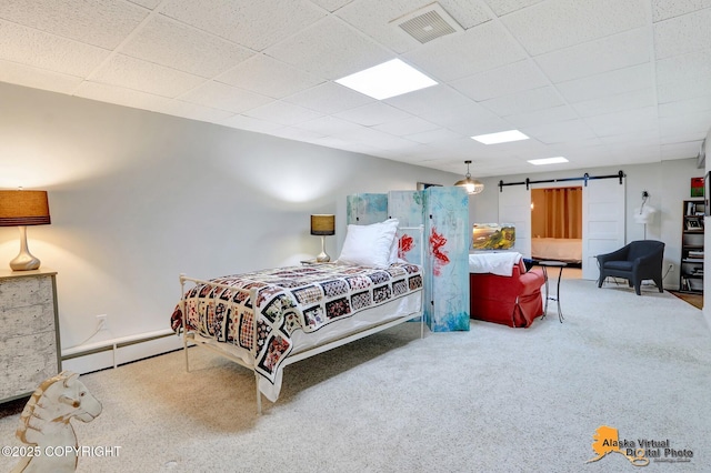 carpeted bedroom with a paneled ceiling, visible vents, a barn door, and baseboard heating