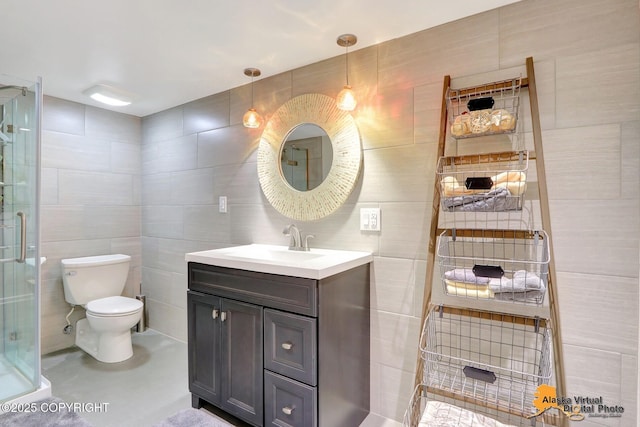 full bath featuring vanity, tile walls, toilet, and a stall shower