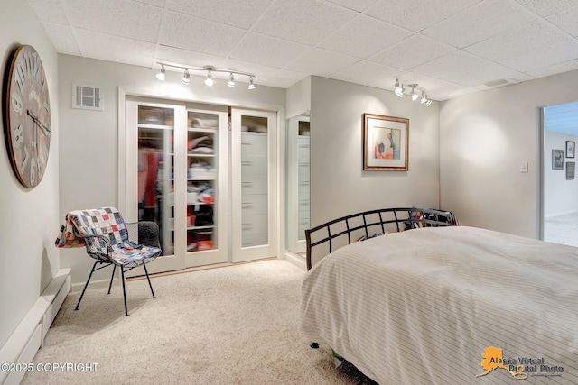 carpeted bedroom featuring track lighting and visible vents