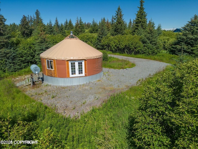 view of side of property with a forest view, an outdoor structure, and driveway