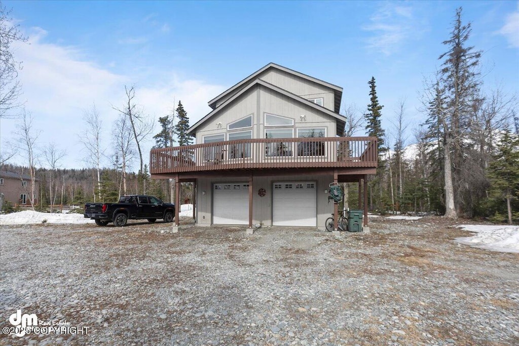 rustic home with an attached garage, dirt driveway, and a wooden deck