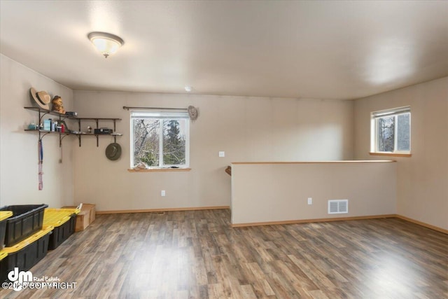 unfurnished room featuring visible vents, a healthy amount of sunlight, baseboards, and wood finished floors