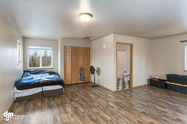 bedroom with a closet, ensuite bath, baseboards, and wood finished floors