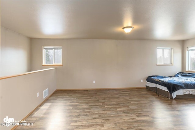 unfurnished bedroom with visible vents, baseboards, and wood finished floors