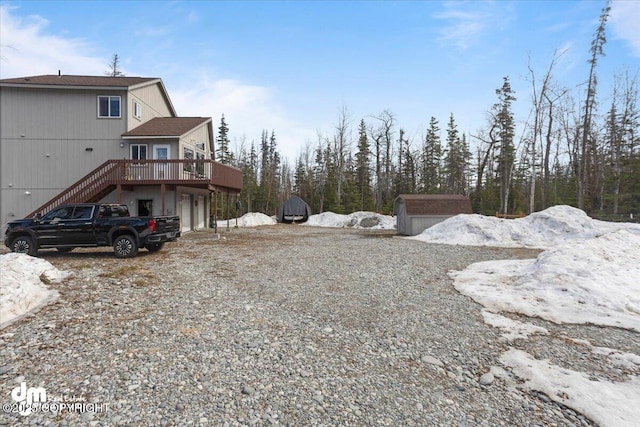 view of yard featuring an outbuilding, driveway, stairway, an attached garage, and a wooden deck