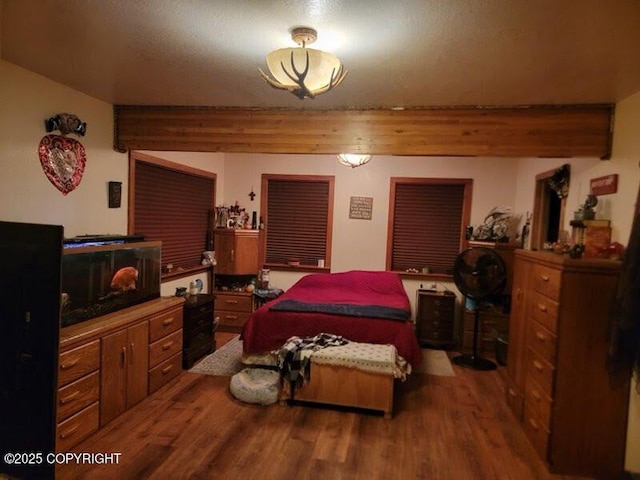 bedroom featuring beamed ceiling and wood finished floors