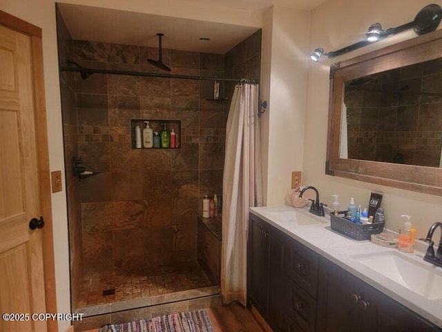 bathroom featuring double vanity, a tile shower, and a sink