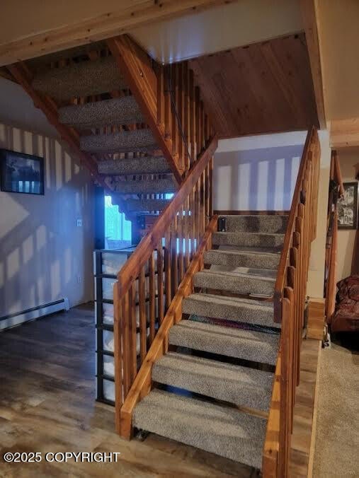 staircase featuring wood finished floors and a baseboard radiator