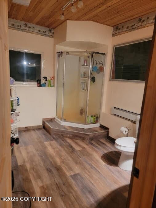 full bathroom with a shower stall, a baseboard heating unit, toilet, wooden ceiling, and wood finished floors