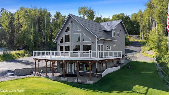 back of property featuring a deck, a patio, metal roof, and a yard