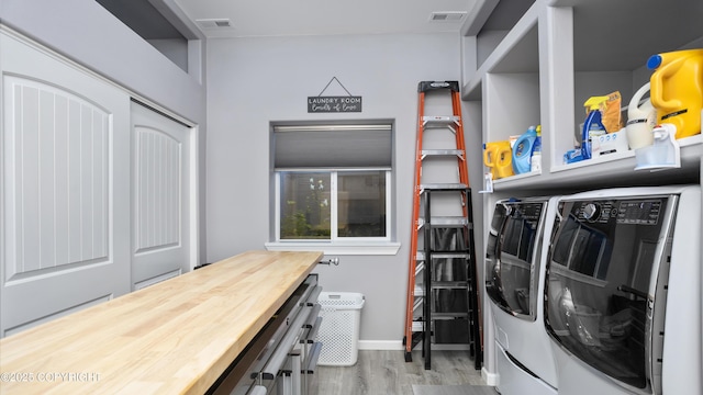 laundry room with laundry area, wood finished floors, separate washer and dryer, and visible vents