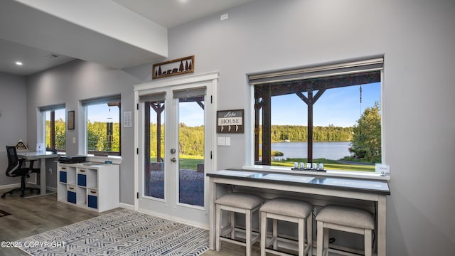 doorway featuring a water view, wood finished floors, recessed lighting, french doors, and baseboards