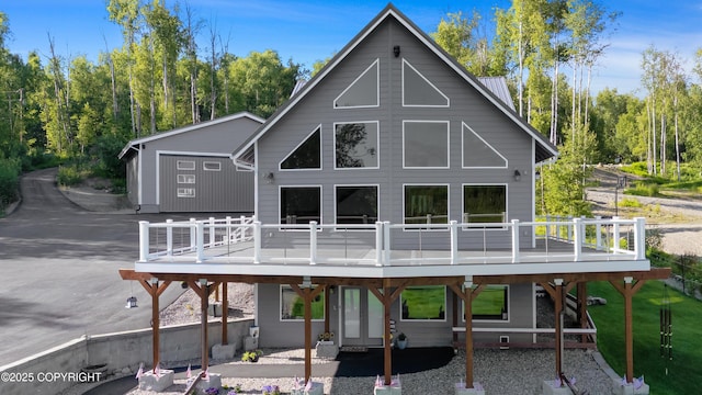 back of house with a patio area, a wooden deck, and metal roof