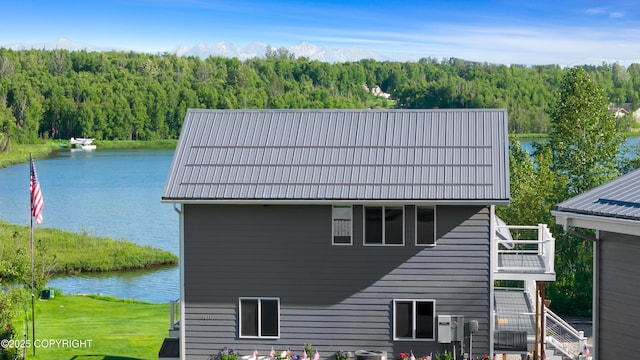 exterior space with a wooded view, metal roof, and a water view