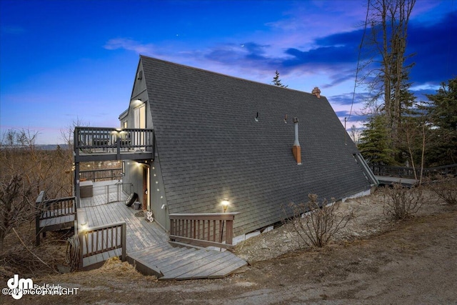 view of home's exterior featuring a deck, a balcony, and roof with shingles