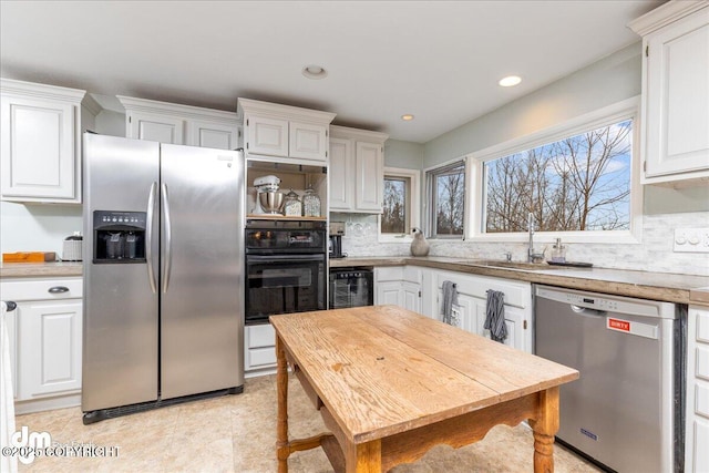 kitchen featuring beverage cooler, backsplash, appliances with stainless steel finishes, white cabinets, and light countertops