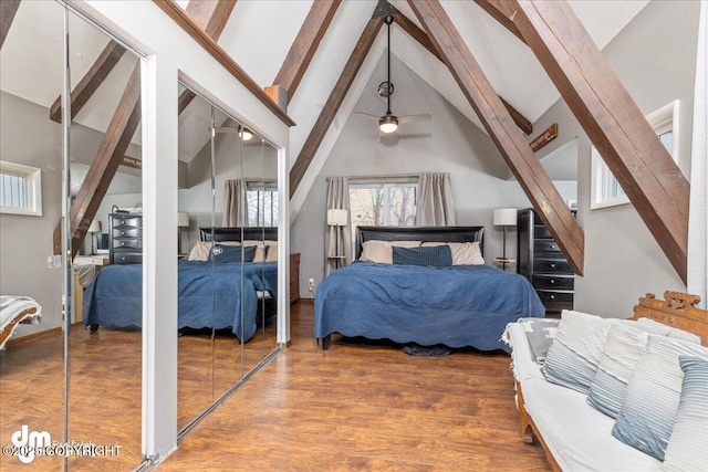 bedroom with beamed ceiling, multiple closets, high vaulted ceiling, and wood finished floors