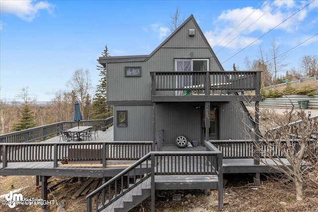 back of property featuring stairway, outdoor dining area, and a deck