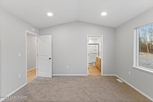 unfurnished bedroom featuring visible vents, baseboards, light colored carpet, and lofted ceiling