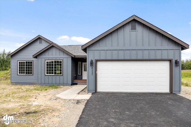 view of front facade with driveway, an attached garage, board and batten siding, and roof with shingles