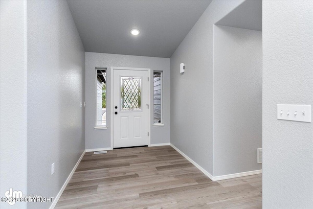 entryway with visible vents, wood finished floors, baseboards, and a textured wall