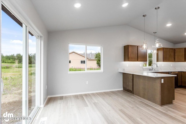 kitchen featuring vaulted ceiling, a healthy amount of sunlight, light wood-type flooring, and a sink