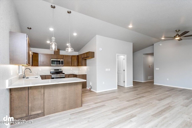 kitchen with stainless steel appliances, light wood-type flooring, light countertops, and a sink