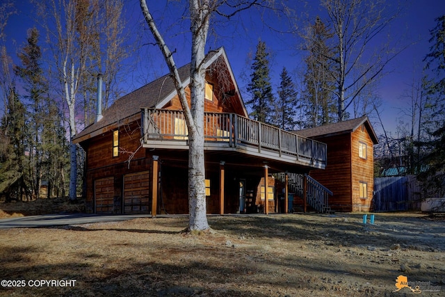 view of front of home with stairway, an attached garage, driveway, and a deck