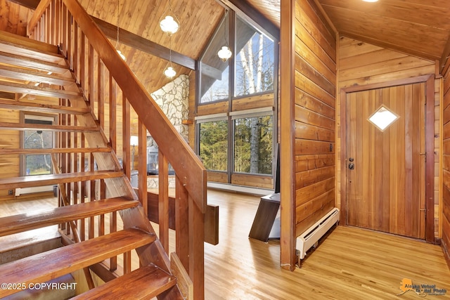 stairway featuring wooden walls, wooden ceiling, wood finished floors, high vaulted ceiling, and a baseboard radiator